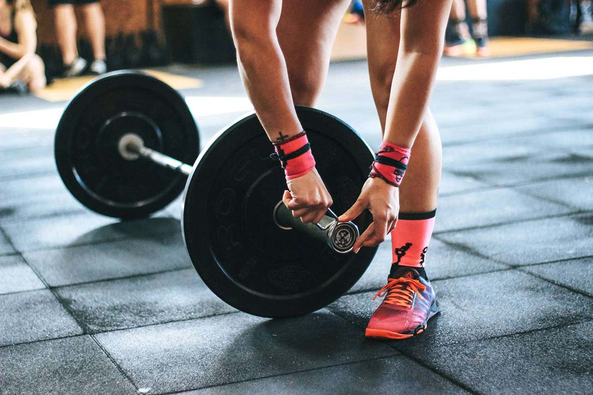 About Sport Conwy. Photo of a weightlifter setting up weights.